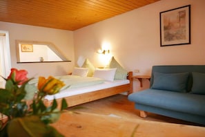 Een kamer met een bed, een slaapbank, een wandlamp en een ingelijste foto.