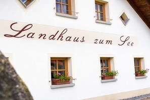 A building with a sign that reads 'Landhaus zum See' and features multiple windows with flower boxes. - on the farm Trout Riding Stable (Neureichenau)