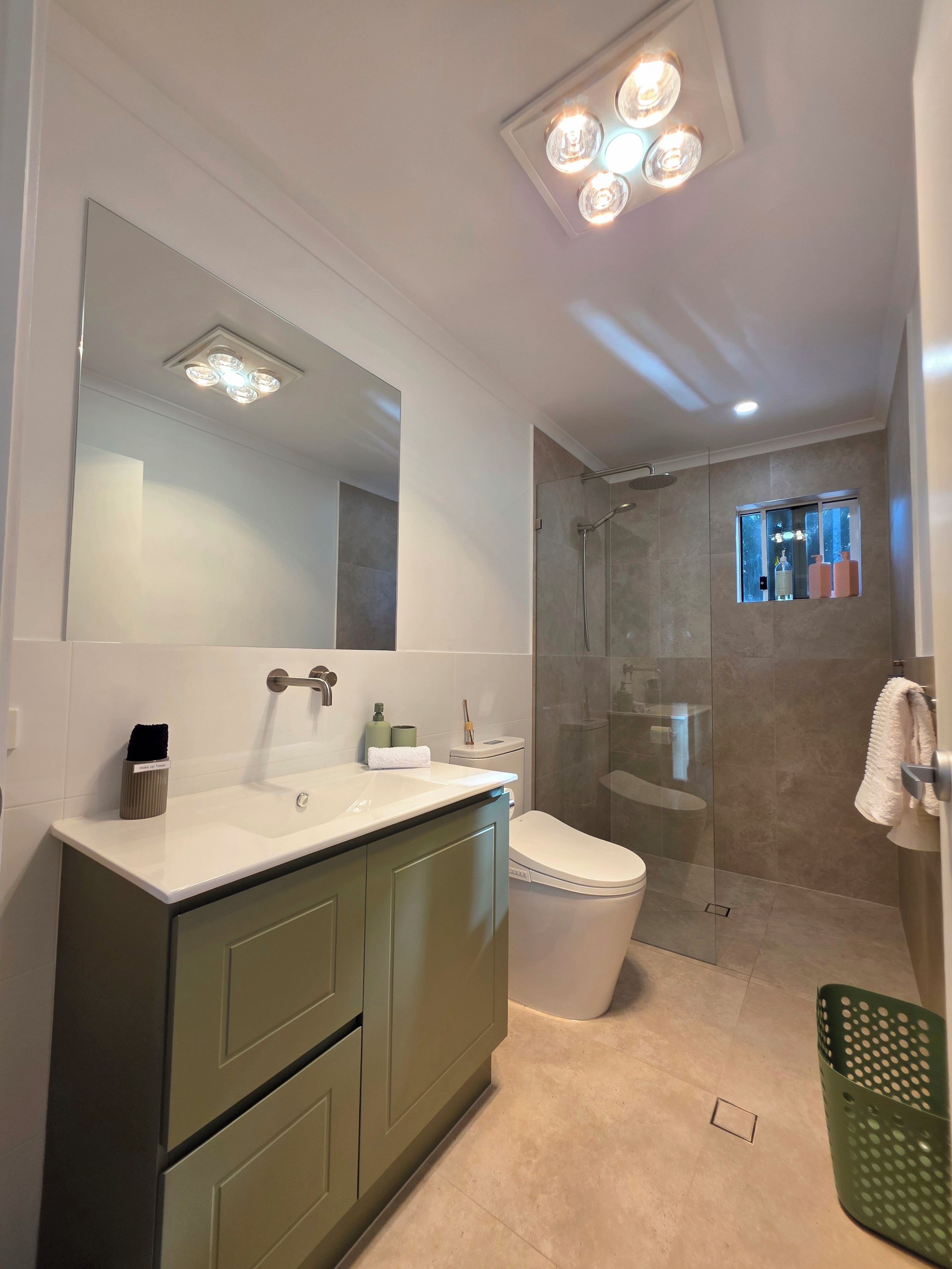 A modern bathroom with a large mirror, a sink, a toilet, and a shower area.