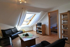 Ein modernes Wohnzimmer mit Schlafkoje, Fernseher und Bücherregal.
