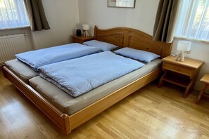 A double bed with a wooden headboard, two bedside tables with lamps, and a window with curtains. - Holiday apartment with 1 bedroom (Hopfen am See)
