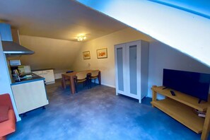 A compact living space with a kitchenette, dining area, and a TV on a wooden stand. - Holiday apartment with 1 bedroom (Siegburg)
