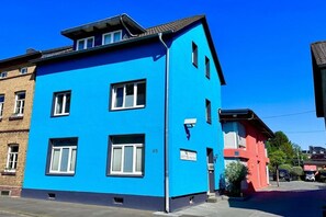 Un edifici de diversos pisos amb una façana blau clar, amb el número 45, i un edifici adjacent de color vermell.