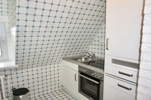 A kitchen with a patterned backsplash, a sink, a stove, and a refrigerator. - Friesenhaus Carl Jensen Holiday Apartment 3 (Wenningstedt-Braderup)