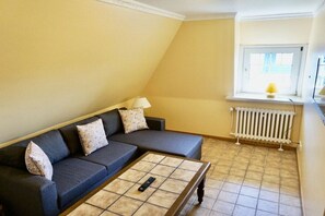 A living room with a sofa, a coffee table, a lamp, and a radiator. - Friesenhaus Carl Jensen Holiday Apartment 3 (Wenningstedt-Braderup)