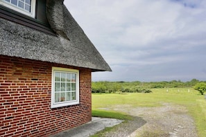Ein Haus mit Ziegelbau und einem Strohdach mit einem Fenster.
