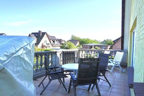 Ein Balkon mit Tisch und Stühlen, mit Blick auf ein Wohngebiet mit Häusern.