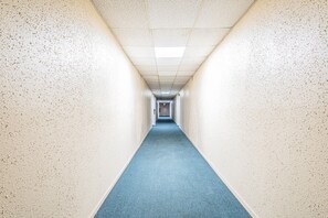 Un long couloir étroit, avec un tapis bleu et des murs blancs.