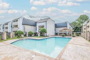 A modern apartment complex with a swimming pool, outdoor seating area, and a covered patio. - 3-Bedroom Condo Near Reliant/NRG Stadium (Houston)