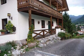 A traditional chalet with a wooden balcony, stone foundation, and potted plants. - Alpenrose Punzenlehen (Schönau am Königssee)