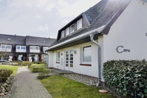Ein zweistöckiges Gebäude mit weißer Fassade, einem sichtbaren Eingang und einer Hinweisschild mit dem Schriftzug 'Cura'.