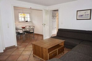 Ein Wohnzimmer mit einer Couch, einem Holztisch und einem Essbereich mit Stühlen und einem Tisch.