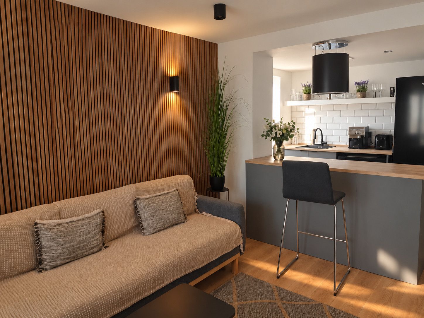 A modern kitchen with a wooden accent wall, a bar area, and a seating area with a sofa and chairs.