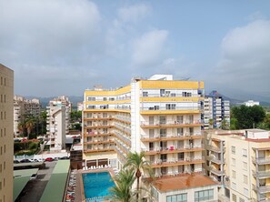 Een meerlaags hotel met balkons, een zwembad en uitzicht op de omliggende stad.
