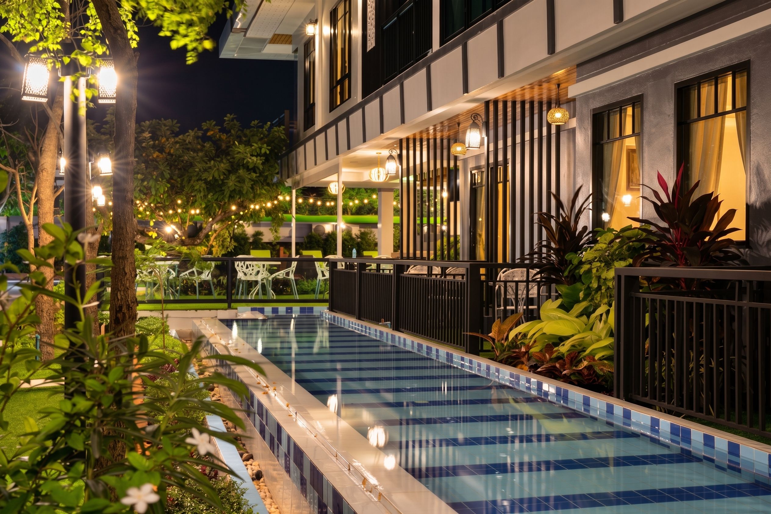 A swimming pool with a tiled edge, surrounded by a fence and potted plants.