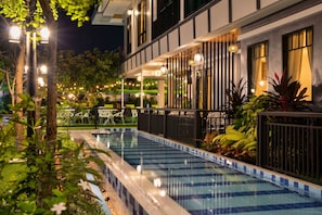 A swimming pool with a tiled edge, surrounded by a fence and potted plants. - Tamnan Pool Resort Pattaya (Pattaya)