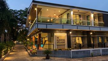 A two-story hotel with a balcony, outdoor seating, and a sign reading 'The Golden Pattaya Hotel & Resort'.