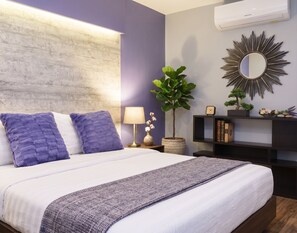A modern bedroom with a bed, a nightstand, a lamp, a mirror, and a wall-mounted air conditioner. - Tamnan Pool Resort Pattaya (Pattaya)