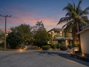 A resort with a modern building, a palm tree, and string lights. - Tamnan Pool Resort Pattaya (Pattaya)