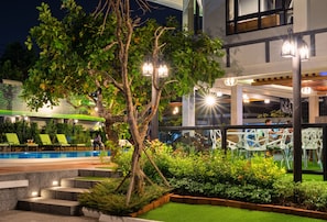 A well-lit outdoor area with a pool, lounge chairs, and a tree. - Tamnan Pool Resort Pattaya (Pattaya)