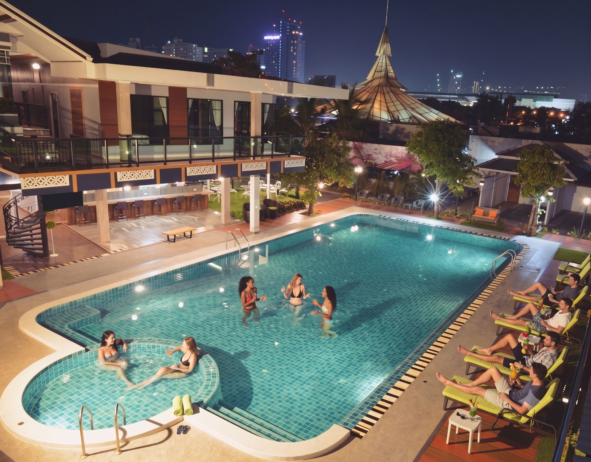 A swimming pool with a sunken hot tub, lounge chairs, and a bar area.