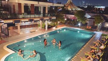 A swimming pool with a sunken hot tub, lounge chairs, and a bar area.