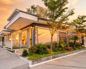 A modern hotel with a balcony, outdoor seating, and a well-maintained garden. - Tamnan Pool Resort Pattaya (Pattaya)