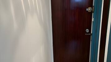 A hallway with a wooden door, a light switch, and a blue door frame.