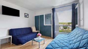 Une pièce comprenant un lit, un canapé, une petite table avec un vase et une fenêtre avec des rideaux.