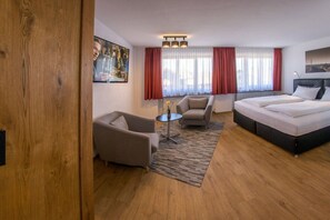 A hotel room with a bed, two armchairs, a small table, and a painting on the wall. - Holiday apartment with 1 bedroom (Oy-Mittelberg)