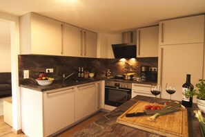A modern kitchen with white cabinets, a dark marble backsplash, and a wooden countertop. - Holiday apartment with 1 bedroom (Oy-Mittelberg)