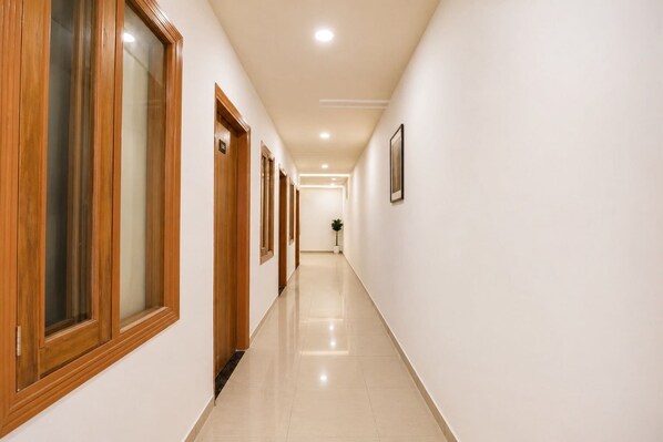 A long, narrow hallway with wooden doors and a tiled floor. - Collection O Guru Nanak Dev University (Amritsar)