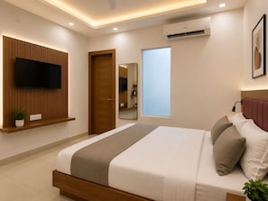 A modern bedroom with a bed, a TV mounted on a wooden panel, a window, and an air conditioning unit.