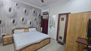 Habitación de hotel con cama, mesitas de noche, armario, ventilador de techo, aire acondicionado y espejo.
