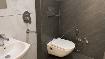 Un baño con lavamanos blanco, inodoro y zona de ducha.