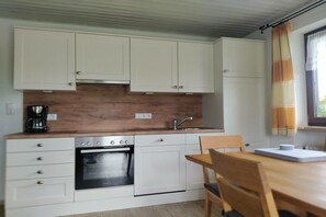 A compact kitchen with white cabinets, a built-in oven, and a wooden countertop. - Ferienhof Waibel - Oberallgäu (Waltenhofen)