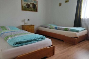A bedroom with two beds, a nightstand, a lamp, and a painting on the wall. - Ferienhof Waibel - Oberallgäu (Waltenhofen)