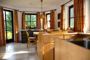Eine Küche mit Holzausstattung, einem Esstisch und einem Fenster mit Vorhängen.