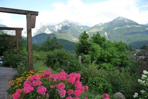 Ein Garten mit rosa Blumen und einer Holzpergola.