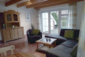 A living room with a sofa, armchair, and a wooden cabinet. - Holiday home with 2 bedrooms (Wangerland \/ Hooksiel)