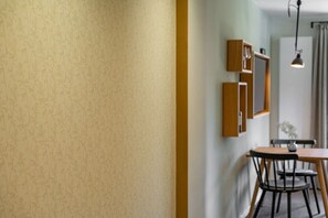 A room with a patterned wall, a wooden table with chairs, a hanging light fixture, and a mirror on the wall. - Holiday apartment with 1 bedroom (Oberstdorf)
