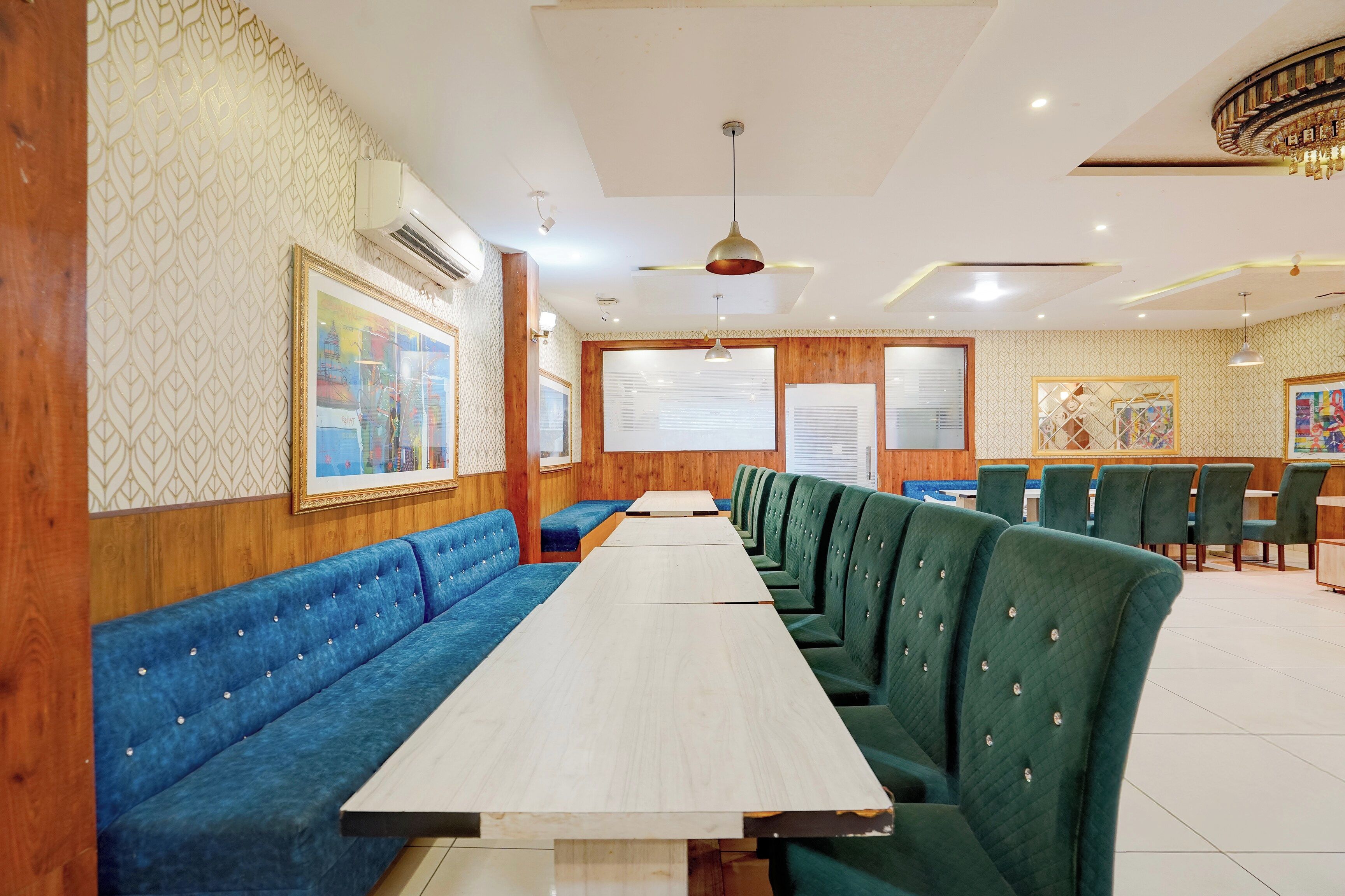 A restaurant with long wooden tables and green upholstered booths.