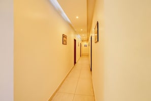 A hotel corridor with a tiled floor, doors, and framed pictures on the walls. - Townhouse Kurukshetra University (Kurukshetra)