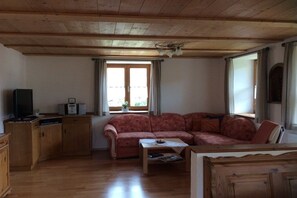 A living room with a wooden ceiling, a sofa, a coffee table, and a television on a wooden cabinet. - in the Vogler House Apartment (Bad Hindelang)