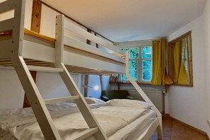 A bunk bed room with a window, a radiator, and a chair. - Holiday apartment with 1 bedroom (Lindau)