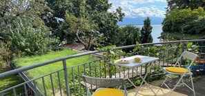Ein Balkon mit Tisch, Stühlen und Blick auf einen See.