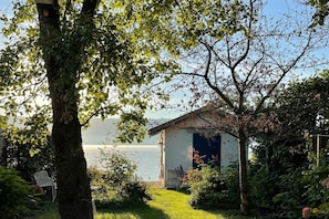 A lakeside property with a small building, a chair, and a table. - Holiday apartment with 1 bedroom (Lindau)