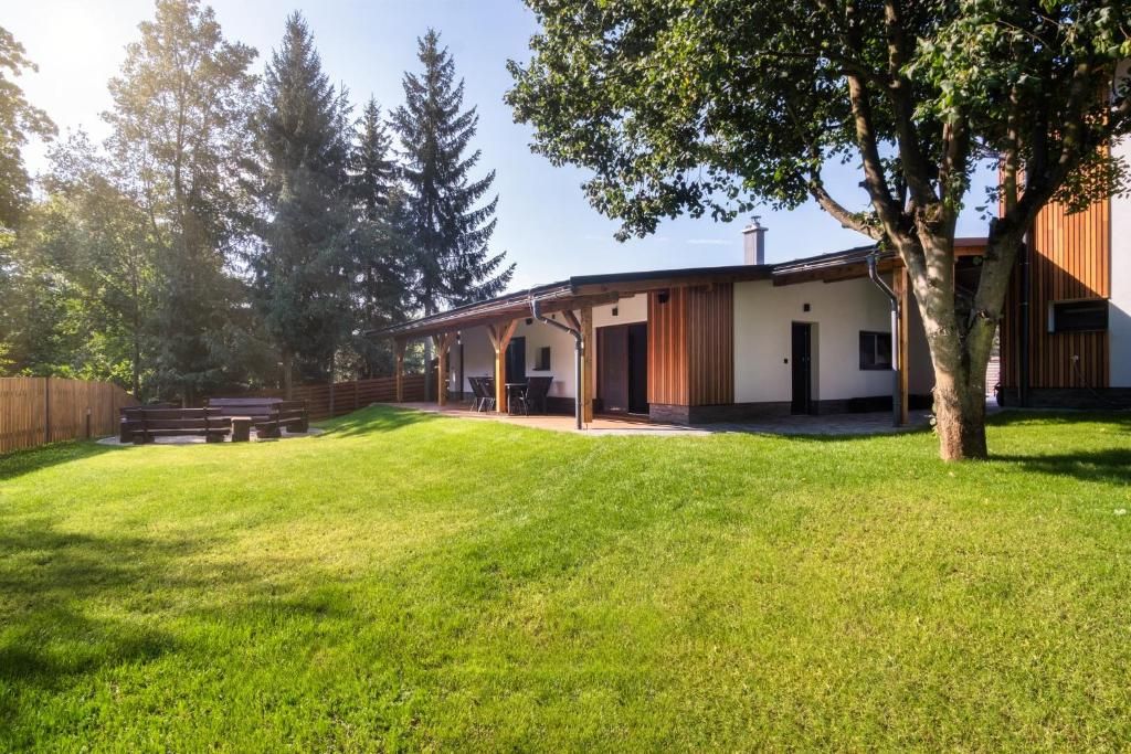 A modern house with a covered patio, a lawn, and a wooden fence.