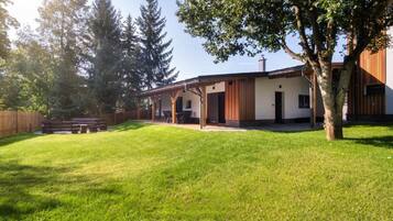 A modern house with a covered patio, a lawn, and a wooden fence.