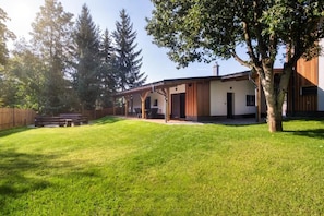A modern house with a covered patio, a lawn, and a wooden fence. - RONI Apartments Krkonoše (Černý Důl)